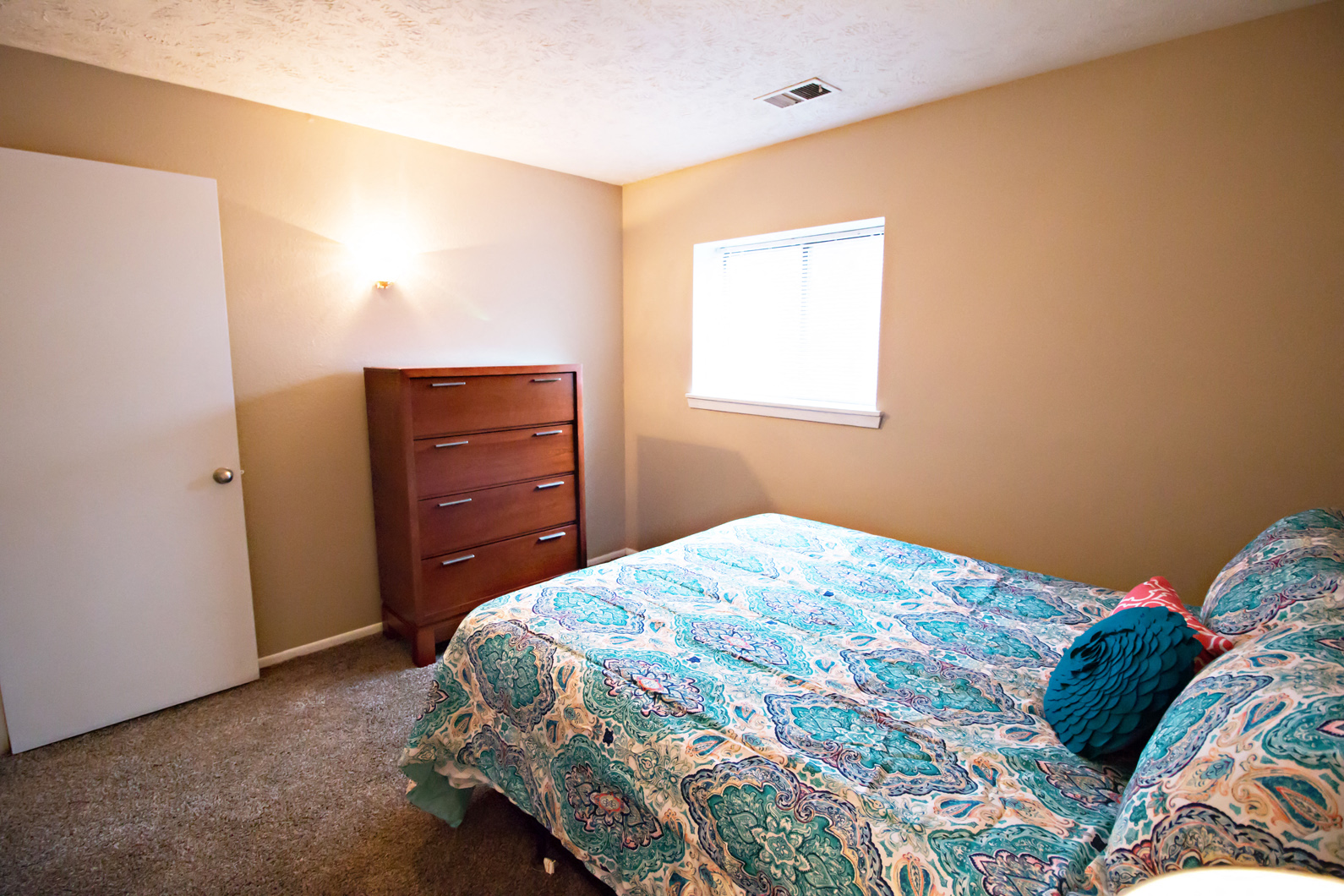 a bedroom with a bed and a dresser and a window