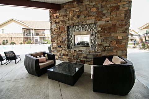 a living area with chairs and a stone fireplace