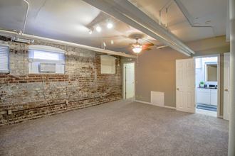 an empty room with a brick wall and a ceiling fan