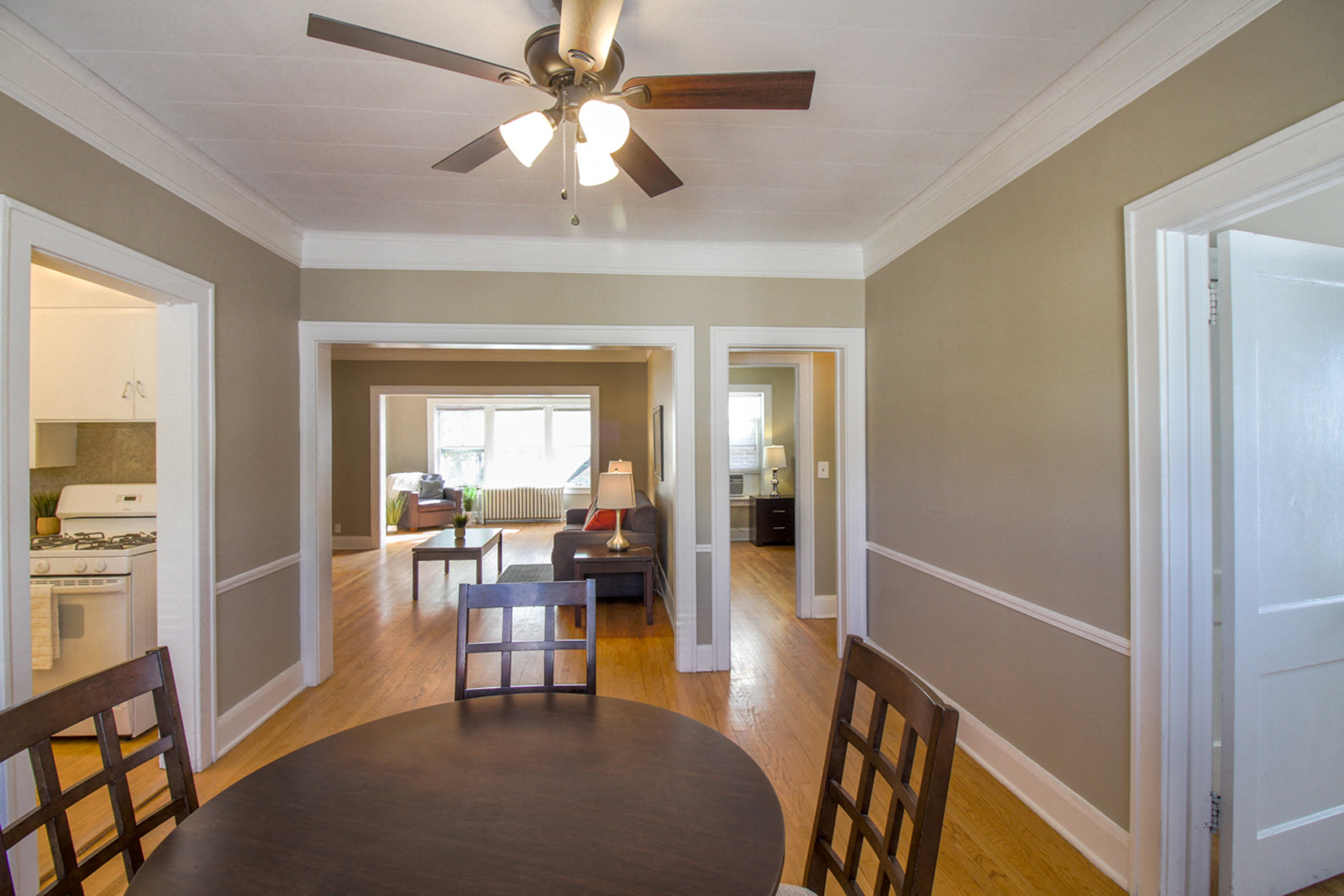 a dining room and living room with a table and a ceiling fan
