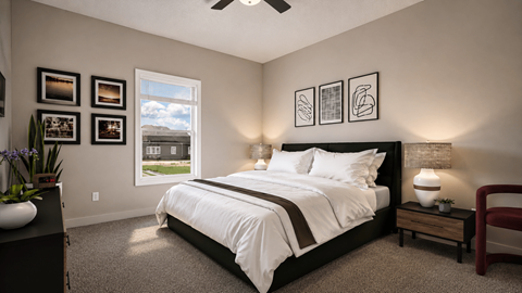 A bedroom with a large bed, a ceiling fan, and pictures on the wall.