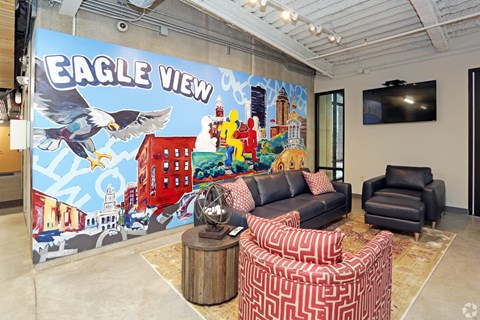 A living room with a large mural on the wall and a TV mounted above the fireplace.