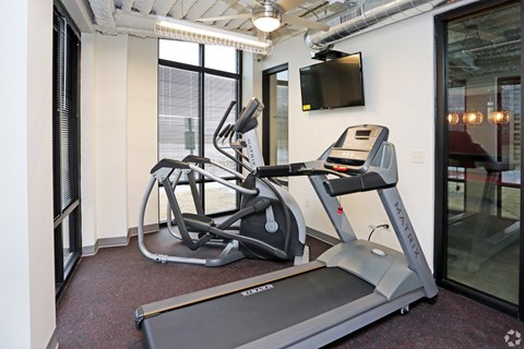 A treadmill and a stationary bike are in a gym.