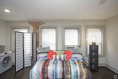 A bedroom with a bed in the center and a washing machine to the left.