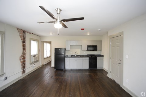 A kitchen with white cabinets and a black fridge is shown.