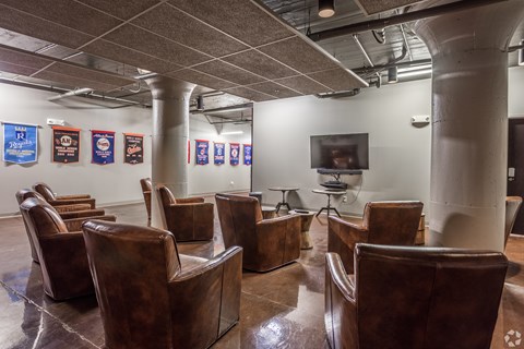 A conference room with brown leather chairs and a television on the wall.