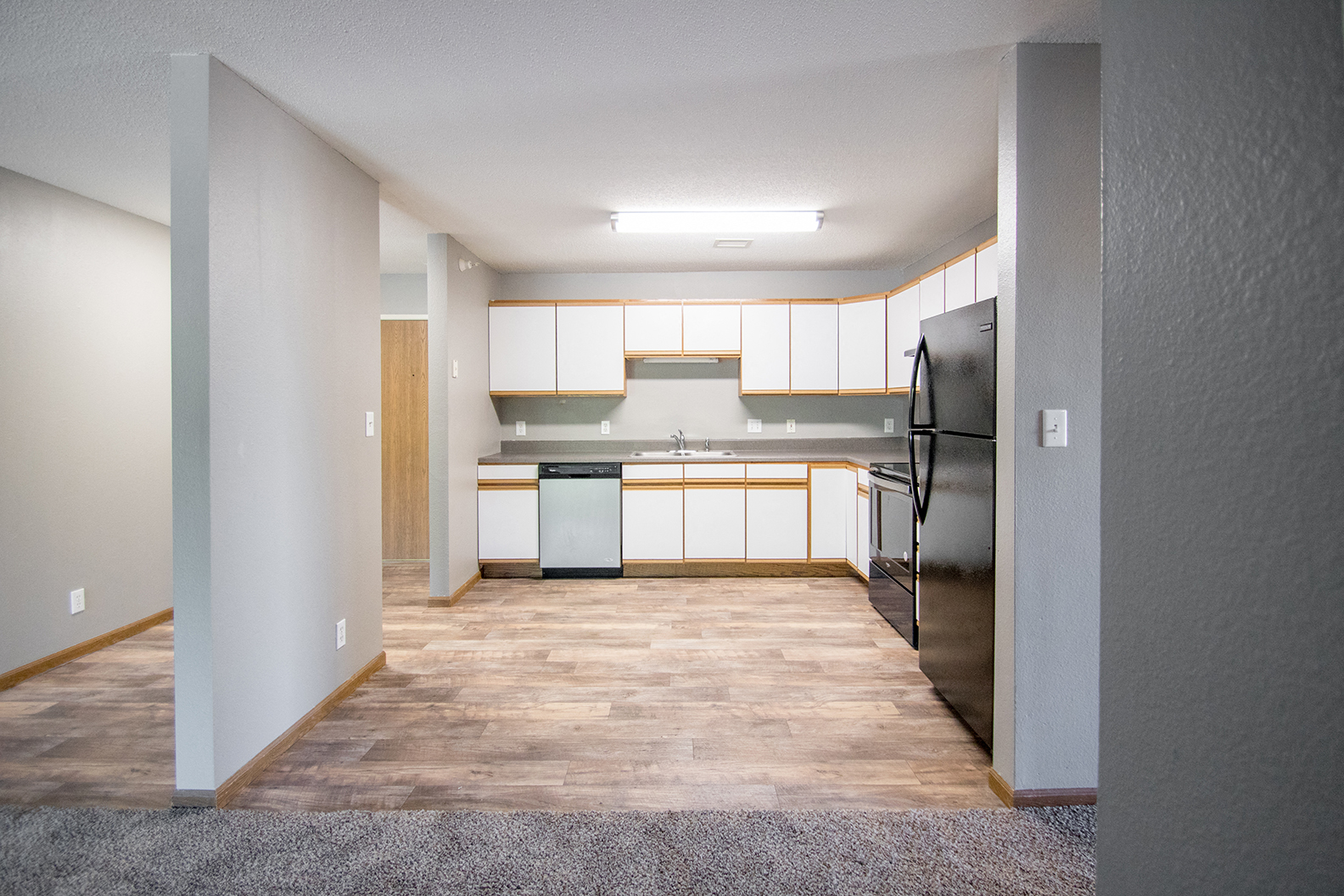 an empty kitchen with white cabinets and a stainless steel refrigerator
