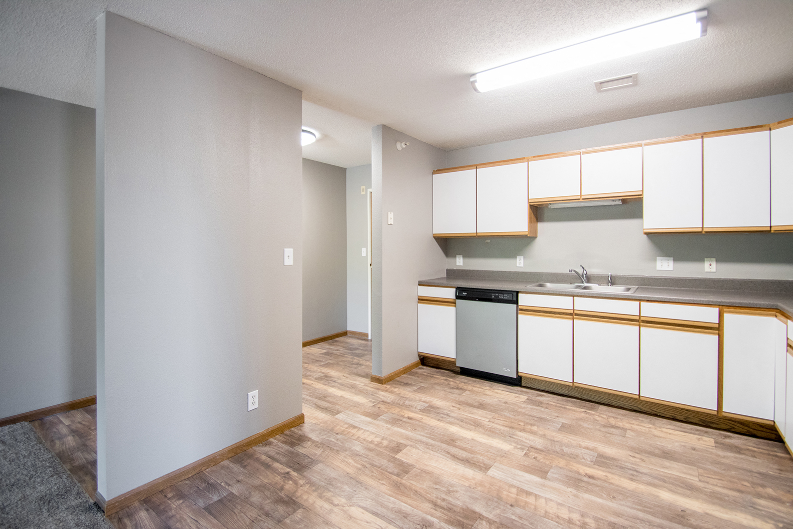 an empty kitchen with white cabinets and a stainless steel dishwasher