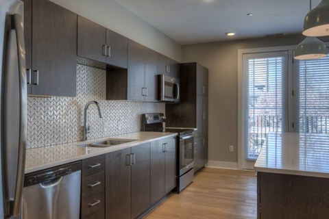 A kitchen with dark wood cabinets and a white tile backsplash.