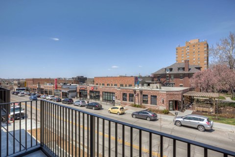 A view of a street from a balcony with cars and buildings.