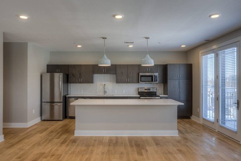 A modern kitchen with wooden floors and a central island.