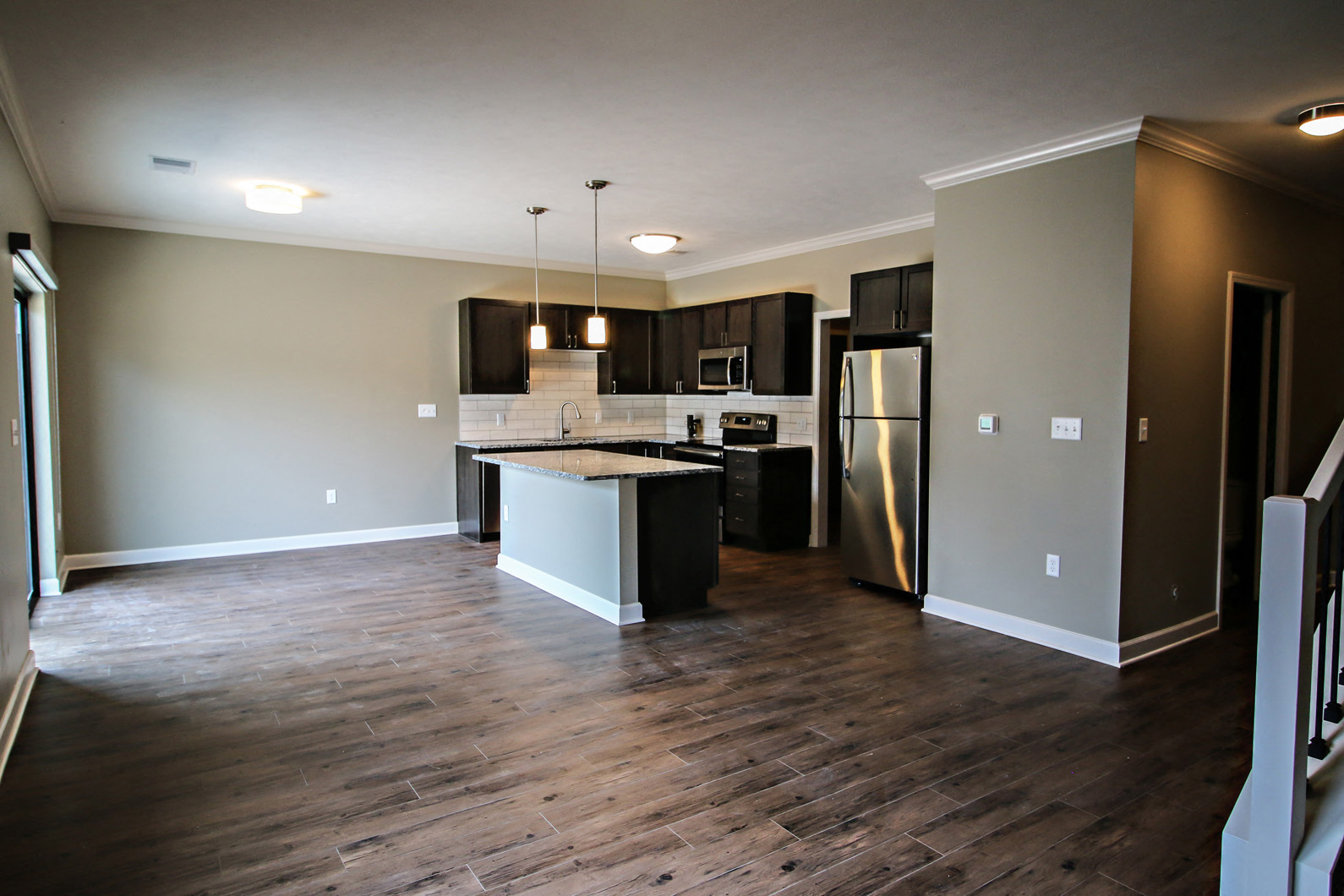 a kitchen and living room with wooden floors and stainless steel appliances