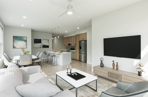 A modern living room with a white sofa set, a glass coffee table, and a flat-screen TV mounted on the wall.