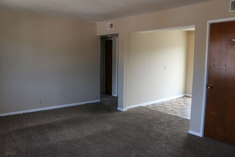 a living room with carpet and a door into a hallway