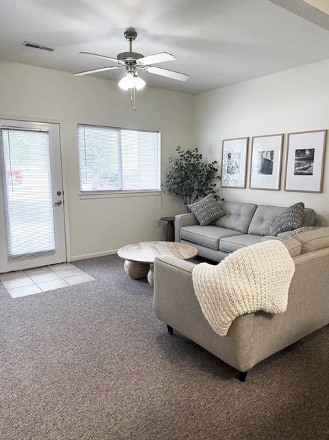 A living room with a grey couch and a ceiling fan.