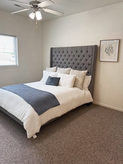 A bedroom with a large bed and a ceiling fan.