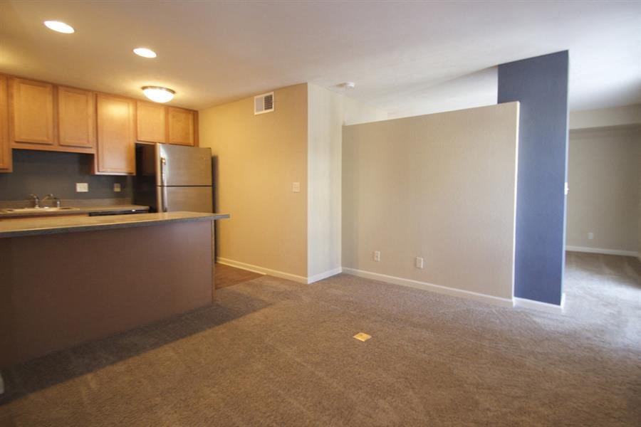 an empty room with a kitchen and a refrigerator