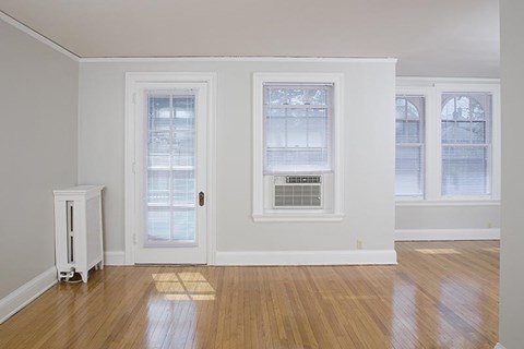 an empty living room with a door and three windows
