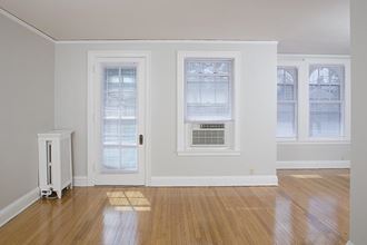 an empty living room with a door and three windows