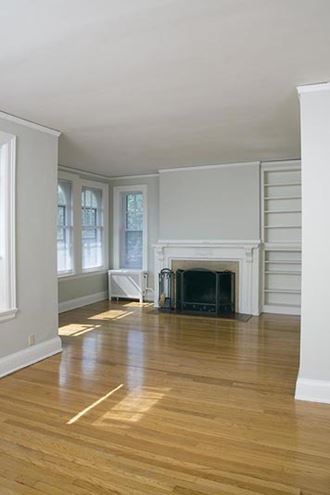 an empty living room with a fireplace and wooden floors