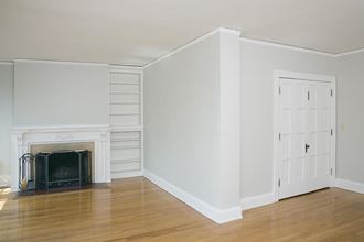 an empty living room with a fireplace and white walls