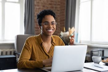 a woman sitting at a table with a laptop computer