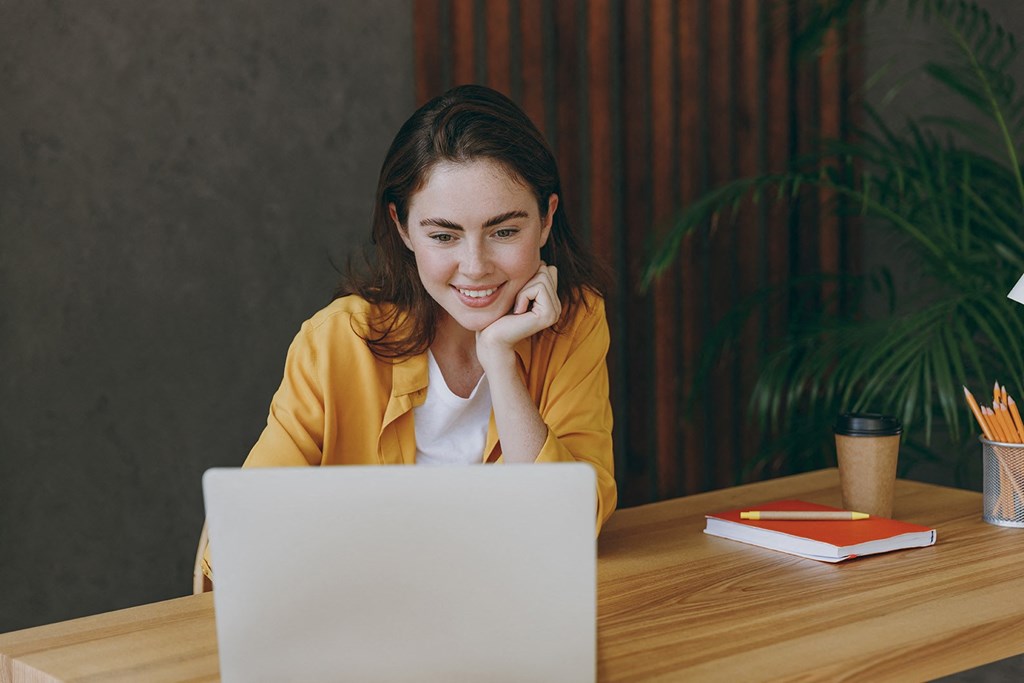 a woman sitting at a table with a laptop computer