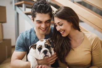 a couple holding a bulldog in their living room