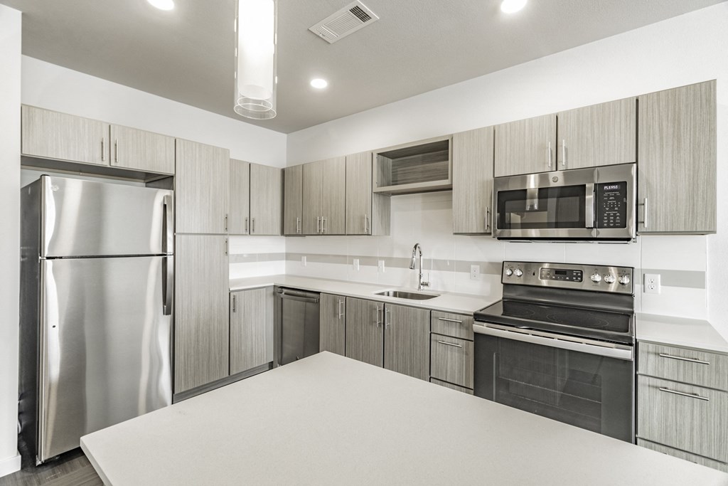One and two Bedroom Apartment Homes with Large Kitchens with ample storage and light cabinets, quarts countertops and stainless steel appliances at Pinnacle Heights Apartments in Rogers, Arkansas
