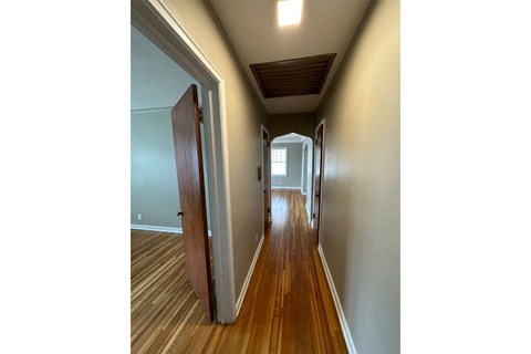 A hallway with a wooden floor and a white door.