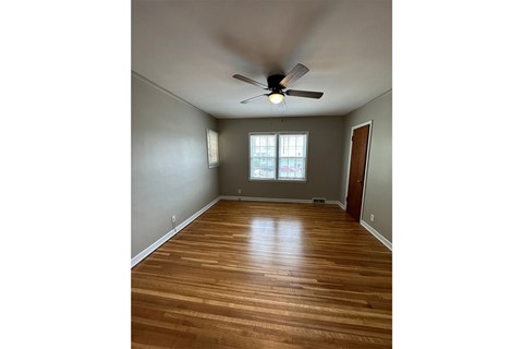 A room with a ceiling fan and wooden flooring.