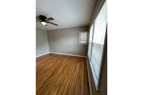 A room with a ceiling fan and wooden flooring.