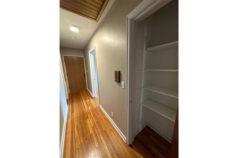 A hallway with a wooden floor and white walls.