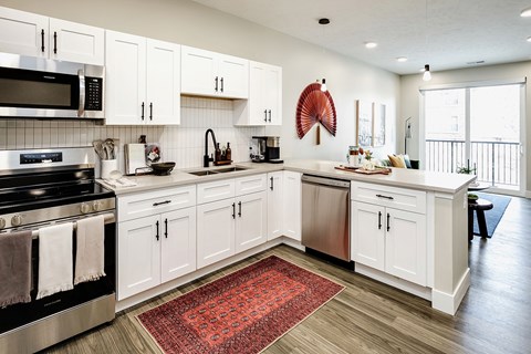 A kitchen with white cabinets and a red rug on the floor.