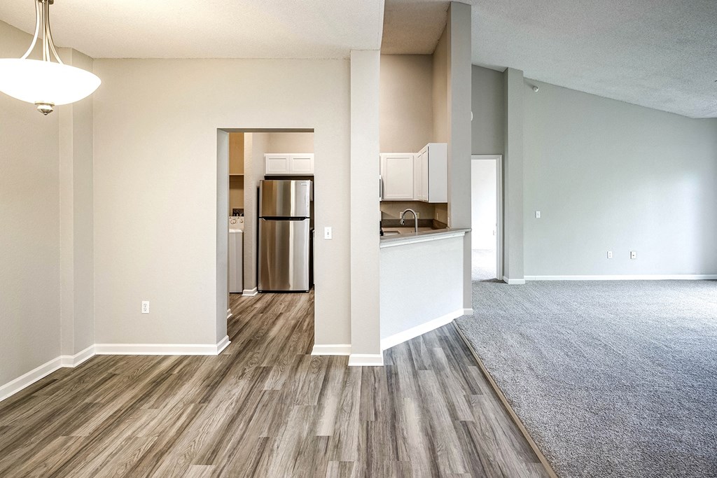 an empty living room and kitchen with wood flooring