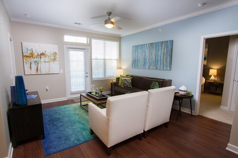 A living room with a white couch and a painting on the wall.