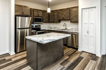 Sandstone cabinets, white marbled countertops, plank flooring, stainless steel appliances