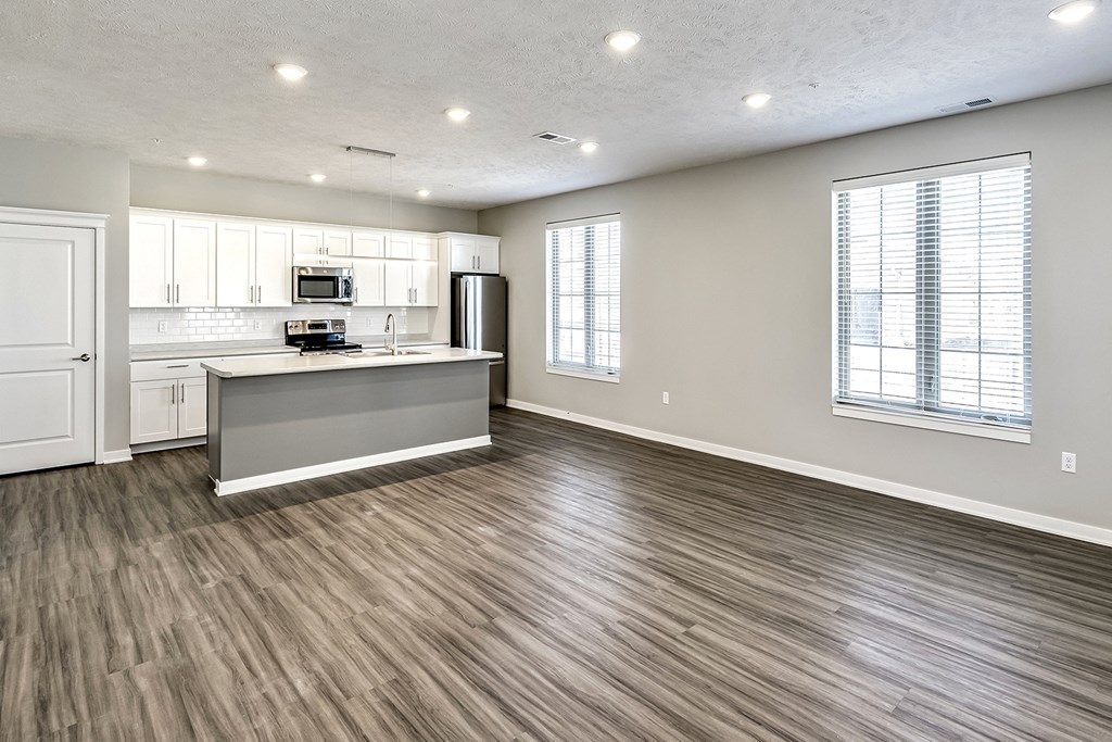 an empty room with a kitchen and a wooden floor