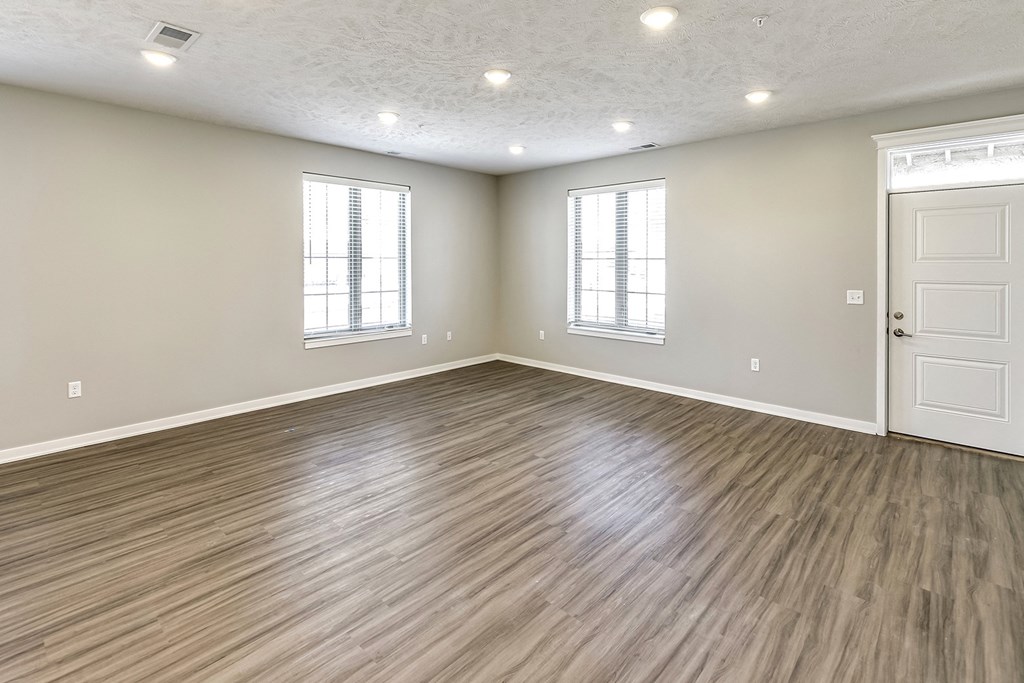an empty living room with vinyl flooring and white walls
