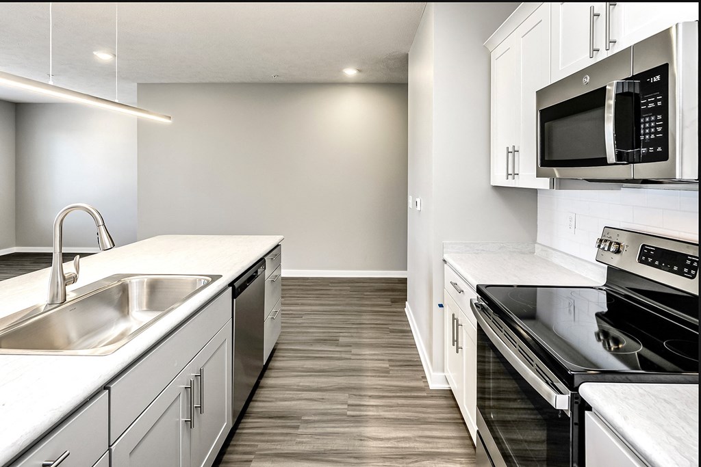 an empty kitchen with stainless steel appliances and white cabinets