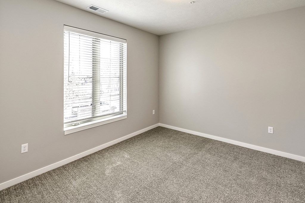 an empty room with a window and carpet