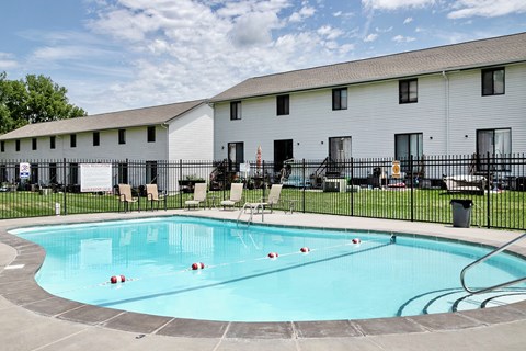 A swimming pool in front of a white building with a black fence.