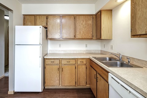 A kitchen with a white refrigerator and wooden cabinets.
