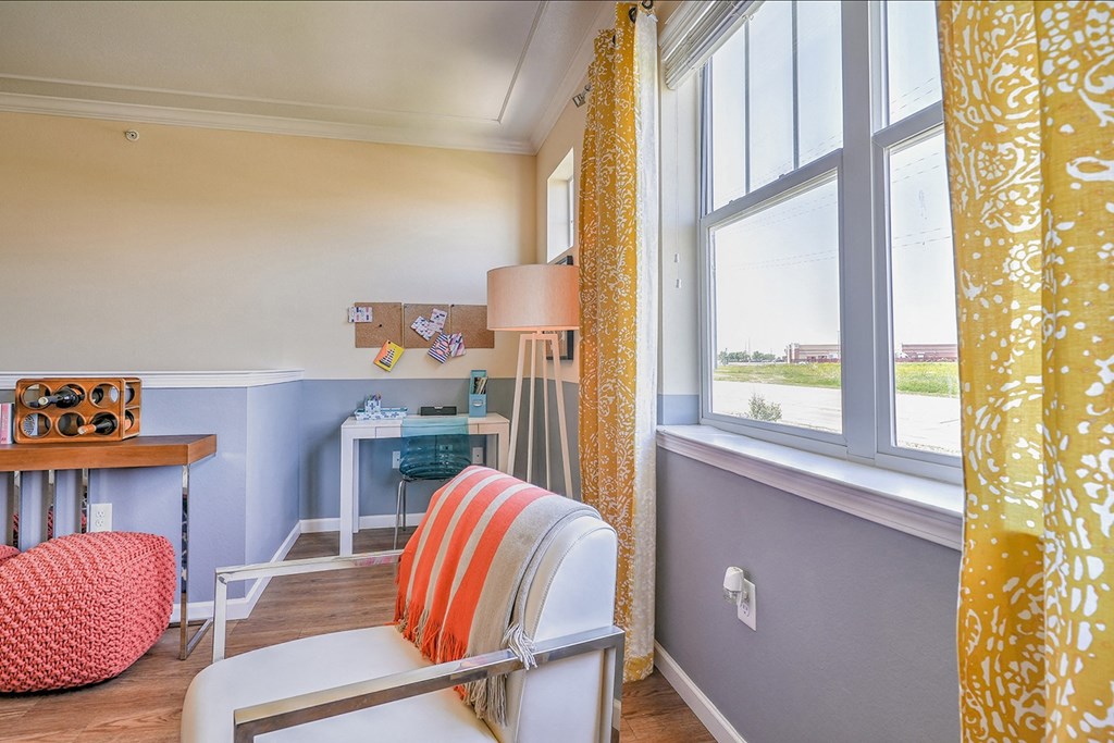 a room with a desk and chair and a window with yellow curtains