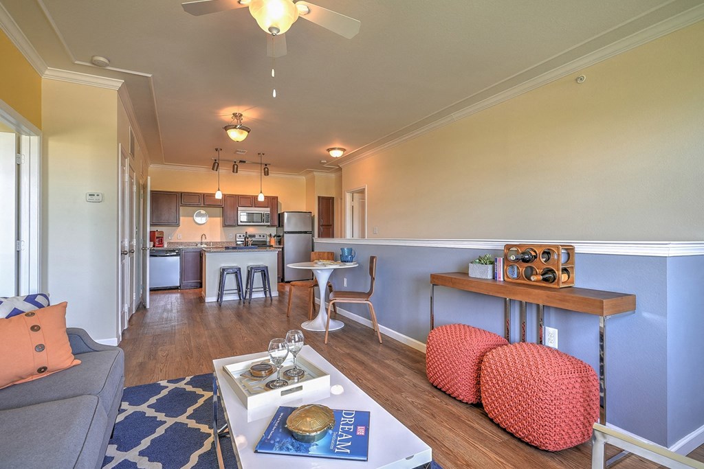 a living room with a couch a table and a chair and a kitchen in the background