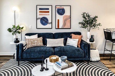 A living room with a blue couch and two framed artworks on the wall.