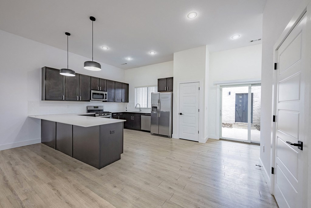 an open kitchen and living room with a refrigerator and a sink
