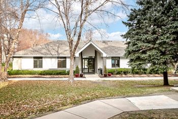 the front of a white house with trees and a sidewalk