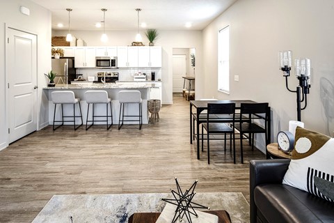 a view of a living room and a kitchen with a table and chairs