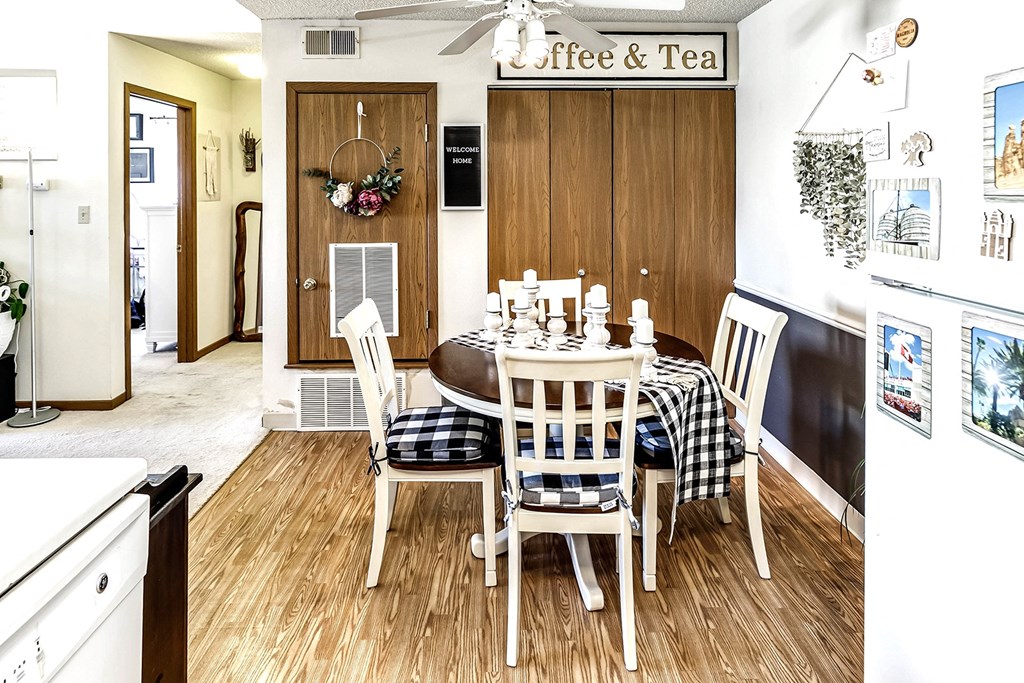 a dining room with a table and chairs and a kitchen with a refrigerator and